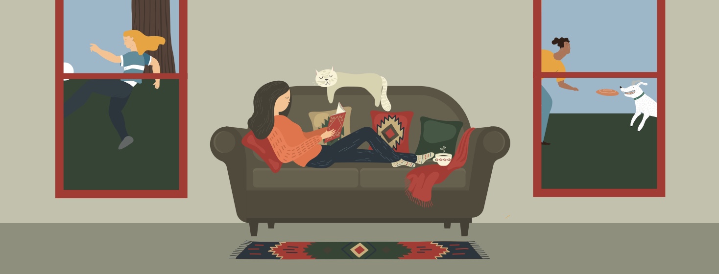 a woman sitting on her couch with a cup of tea and her cat, reading a book